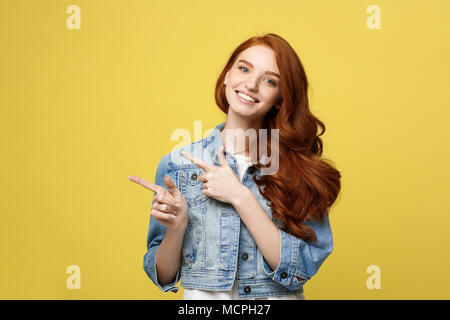 Lifestyle Concept: Happy excited cuacaisan tourist girl pointing finger on copy space isolated on golden yellow background Stock Photo