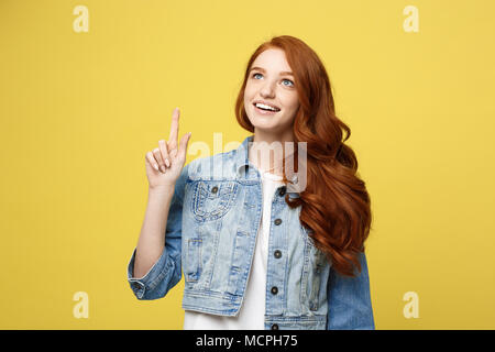 Lifestyle Concept: Happy excited cuacaisan tourist girl pointing finger on copy space isolated on golden yellow background Stock Photo