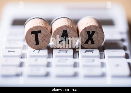 Close-up Of Tax Text On Cork Over Calculator Stock Photo