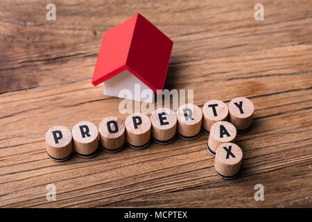 Elevated View Of House Model Near Blocks With Property And Tax Text On Wooden Background Stock Photo