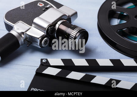 Close-up Of Movie Camera With Film Reel And Clapper Board On Wooden Desk Stock Photo