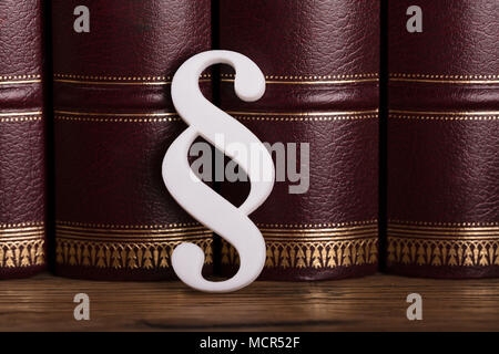 Close-up Of White Paragraph Symbol Leaning On Law Books In Courtroom