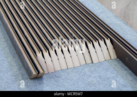 Furniture accessories. Colorful wooden floor for home renovation. Manufacture of skirting boards in a furniture factory. Stock Photo