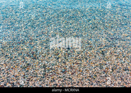 Background of blurred bright colorful sea stones under water. Iridescent sunlight on the stones. Transparent clear water of sea. Toned photo Stock Photo