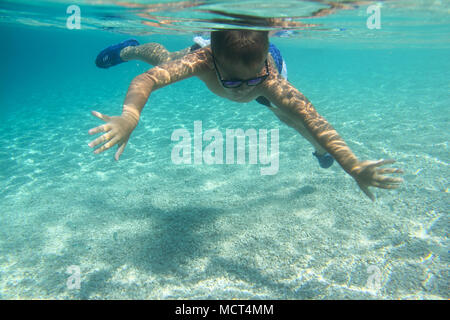 Boy swimming underwater, beautiful view of crystal clear transparent water of Mediterranean sea in Croatia Stock Photo