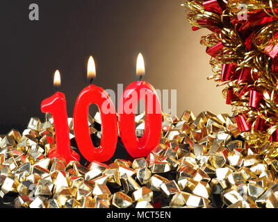 Birthday-anniversary candle showing Nr. 100  Lit red candle good for an anniversary or birthday background. Stock Photo