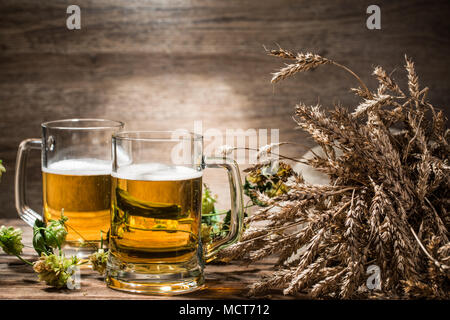 Two mugs of beer next to spikelets on empty background Stock Photo
