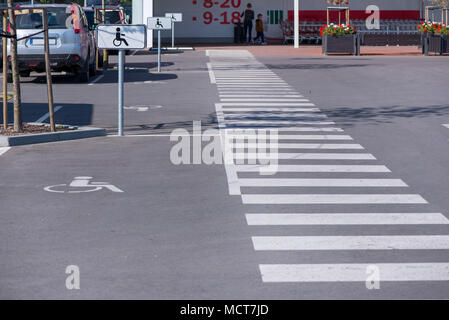 Newly made parking lot next to shopping mall in city centre with green areas and pedestrian crossing. Arrows and signs on asphalt showing rules and di Stock Photo