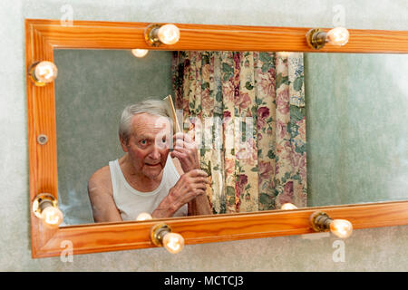 Elderly man looking in the mirror before bedtime Stock Photo