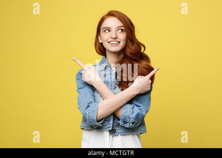 Lifestyle Concept: Happy excited cuacaisan tourist girl pointing finger on copy space isolated on golden yellow background Stock Photo