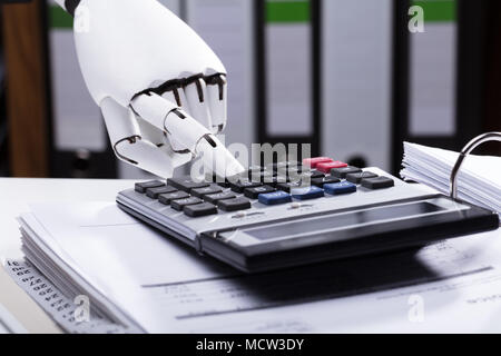 Close-up Of A Robotic Hand Using Calculator Stock Photo