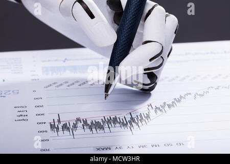 Elevated View Of A Robotic Hand Holding Pen Over Financial Document Stock Photo