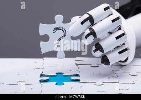 Close-up Of A Robotic Hand Solving Jigsaw Puzzle Stock Photo