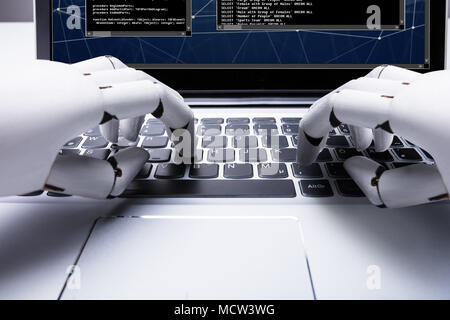 Close-up Of A Robotic Hand Typing On Laptop Keypad Stock Photo
