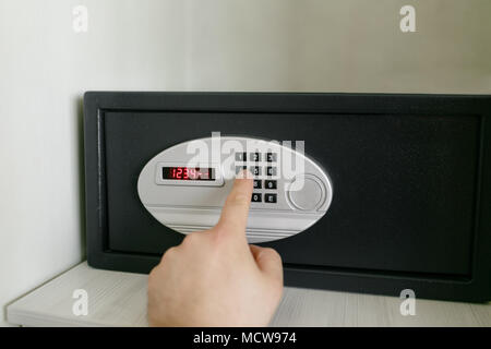 easy password. Hand press key on black safety box in hotel room. Concept safe storage of money and documents Stock Photo