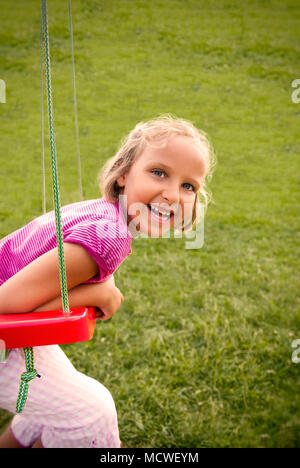 Girl child on a swing in the park. Stock Photo