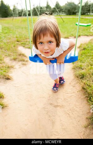 Girl child (three years old) on a swing in the park. Stock Photo