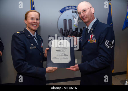 Maj. Alta R. Caputo, the commander of the105th Base Defense Squadron, presents Tech. Sgt. Raymond P. Lucca Jr. with a certification of retirement at Stewart Air National Guard Base, New York, March 4, 2018. The certificate was given during a ceremony to honor his military career.(U.S. Air Force photo by Airman 1st Class Mary Schwarzler) Stock Photo