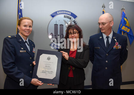 Maj. Alta R. Caputo, the commander of the105th Base Defense Squadron, presents Tech. Sgt. Raymond P. Lucca Jr. wife Ellen Lucca with a certification of retirement at Stewart Air National Guard Base, New York, March 4, 2018. The certificate was given during a ceremony to honor his military career. (U.S. Air Force photo by Airman 1st Class Mary Schwarzler) Stock Photo
