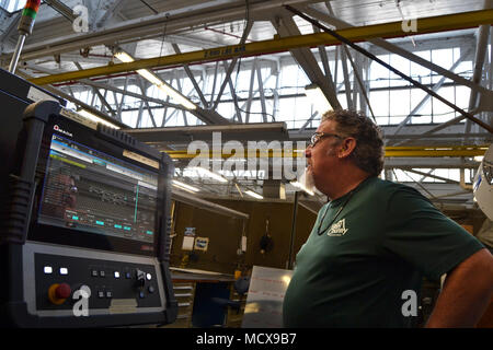 Fleet Readiness Center Southeast is a U.S. Navy aviation maintenance facility in Jacksonville, Florida, responsible for depot-level aircraft support. The archival image documents a sheet metal mechanic monitoring a fiber laser cutter display on March 1, 2018, during machining operations within the production area. Stock Photo