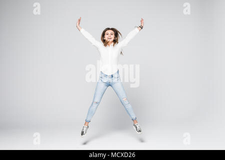 Full length portrait of a young beautiful brunette girl jumping and smiling happily isolated on white background Stock Photo