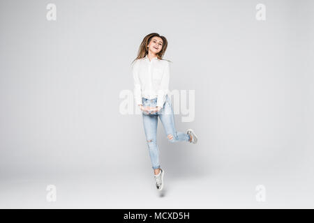 Full length portrait of a young beautiful brunette girl jumping and smiling happily isolated on white background Stock Photo