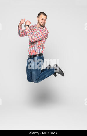 Vertical image of happy man in shirt and jeans which jumping in studio. Stock Photo