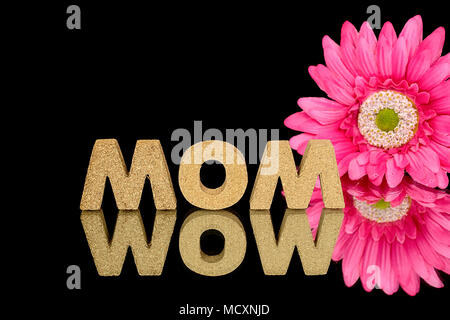 word mom and wow in black mirror reflection with bright pink gerbera daisy Stock Photo