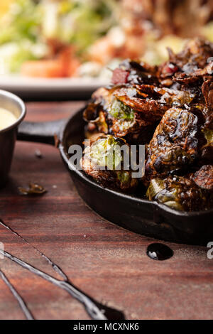 Brussel Sprouts roasted in an iron pan accompanied by a butter dressing on the side Stock Photo