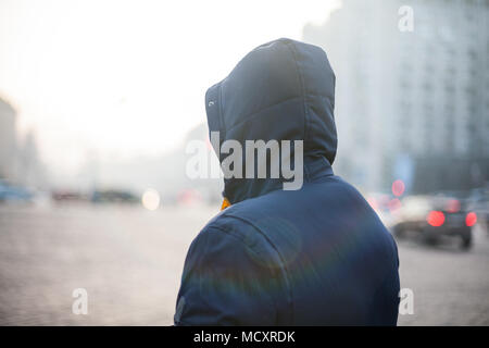 Hipster man in hood walking on city street Stock Photo