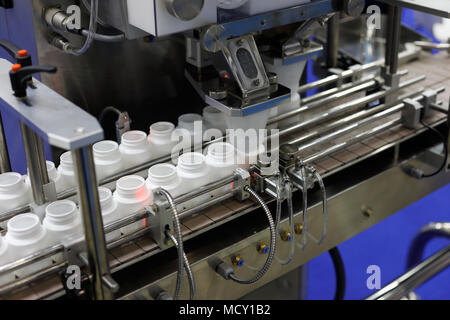 Pharmaceutical packaging line. Bottle filling machine with empty plastic pill bottles. Stock Photo