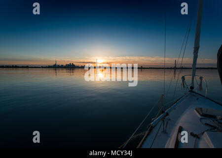 Sailboat on ocean with skyline at distant during sunset, Toronto, Canada Stock Photo