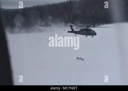 UH-60s assigned to the New York Army National Guard's  3rd Battalion, 142nd Aviation, pull away from a landing zone east of Otsego Lake in Cooperstown, N.Y. after dropping off members of Charlie Company, 403rd Civil Affairs Battalion of the Army Reserve, while conducting  air assault training on, March 3rd, 2018. The mission profile called for the Army Guard aviators to drop the Civil Affairs Soldiers outside a museum whose collections they needed to secure.(N.Y. National Guard photo by Spc. Andrew Valenza) Stock Photo