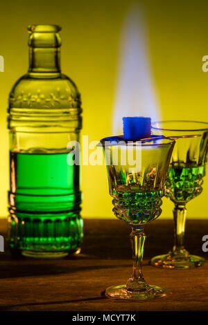 Bottle of absinthe and glasses with burning cube brown sugar. Stock Photo