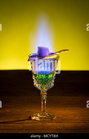 Burning sugar on spoon in glass of absinthe. Stock Photo