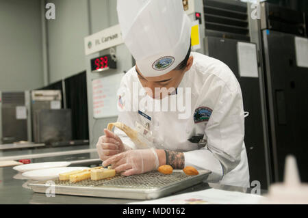 The Joint Culinary Training Exercise (JCTE) is an annual American Culinary Federation–sanctioned military culinary competition held at Fort Lee, Virginia, and organized by the Joint Culinary Center of Excellence. The archival image documents a service member preparing ingredients during the 43rd annual event, conducted March 10–15, 2018, to enhance joint food service proficiency across military branches. Stock Photo