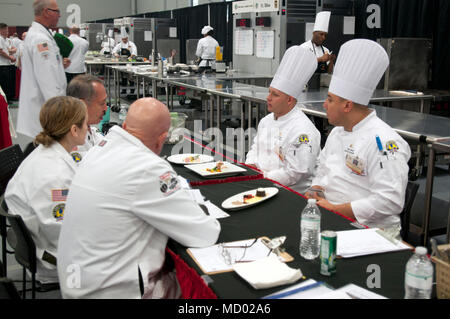 Staff Sgt. Jerald Bonkowski and Sgt. Darmel Carasquilo, both culinary arts specialists from Team Hawaii, receive critiques from the judges during the Joint Culinary Training Event at Fort Lee, Va. March 10, 2018. The 43rd annual JCTE started March 10 at Fort Lee MacLaughlin Fitness Center and continues until March 15. The exercise, administered by the Joint Culinary Center of Excellence, is the largest American Culinary Federation-sanctioned competition in North America. The exercise showcased the talent of more than 220 military chefs from all military services around the globe to include fou Stock Photo