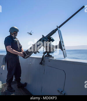 PACIFIC OCEAN (March 28, 2018) Gunner’s Mate 3rd Class Brendon S. Gerry, from Jacksonville, Fla., stands ready at a M2 HB .50 caliber machine gun station during a simulated maritime reaction force visit board search and seizure (MRF VBSS) exercise aboard San Antonio-class amphibious transport dock USS Anchorage (LPD 23).  Anchorage is underway with 13th Marine Expeditionary Unit (MEU) for an amphibious squadron and MEU integration (PMINT) exercise. PMINT is a training evolution between Essex Amphibious Ready Group and 13th MEU, which allows Sailors and Marines to train as a cohesive unit in pr Stock Photo