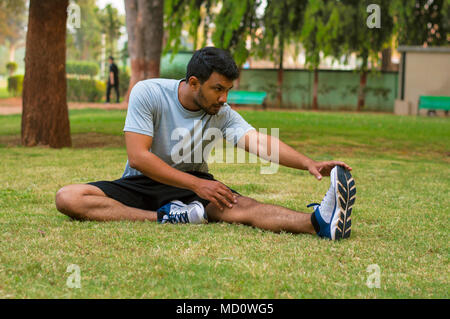 Young guy doing stretching exercise in a park Stock Photo