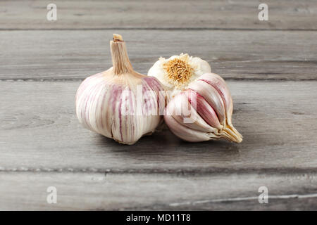 Garlic bulbs, purple cloves under cracked skin on gray wood table. Stock Photo