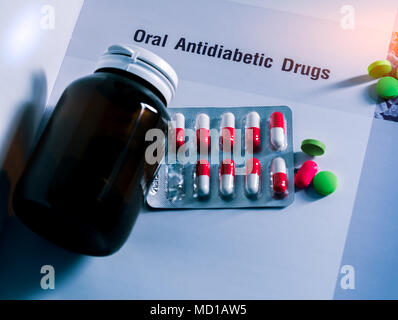 Diabetes drugs in packs and and medicine bottle with blank label placed on textbook. Green tablets and pink-white capsule pills. Diabetes mellitus the Stock Photo