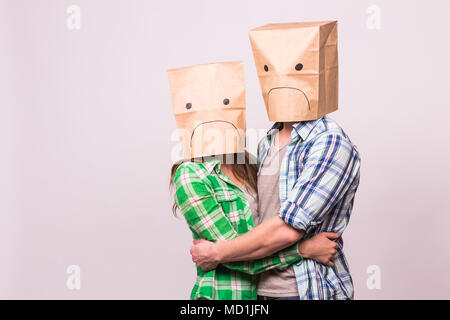 love, family and relationship problems concept - unhappy couple covering their sad faces with paper bag over white background. Stock Photo