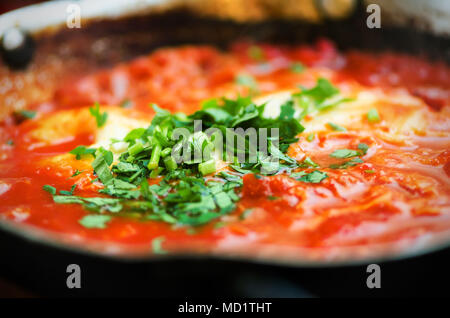 Shakshuka. Traditional jewish food and middle eastern cuisine recipe. Fried eggs, tomatoes, bell pepper and parsley in a pan. Close up, selective focu Stock Photo