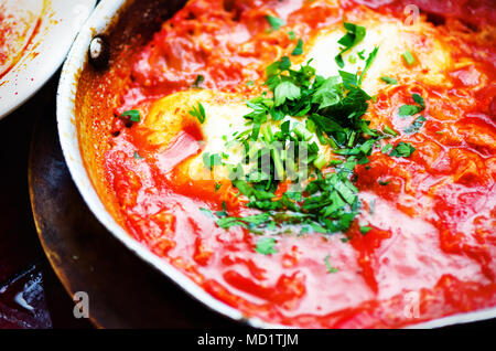 Shakshuka. Traditional jewish food and middle eastern cuisine recipe. Fried eggs, tomatoes, bell pepper and parsley in a pan. Close up, selective focu Stock Photo