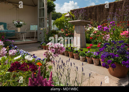 Bright colourful summer flowering plants, stone birdbath & summerhouse - English cottage garden display, RHS Flower Show, Tatton Park, England, UK. Stock Photo