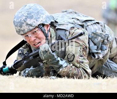 Cpl. Sang Chang Lee, a military policeman with the 557th Military Police Company, 94th Military Police Battalion, and a native of Changwon, Korea, low crawls during the 19th Expeditionary Sustainment Command Best Warrior Competition stress shoot obstacle course, Mar. 7 at Masan, Korea. Stock Photo