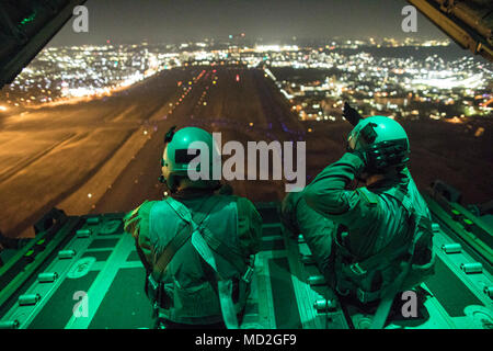 (Left to right) Senior Airman Stephen Clark and Airman 1st Class Matthew Pfeffer, 36th Airlift Squadron C-130J loadmaster, perform a simulated airdrop over Yokota Air Base, Japan, March 26, 2018. Yokota aircrews regularly conduct night flying operations to ensure they are prepared for a variety of contingencies throughout the Indo-Asia Pacific region. Stock Photo