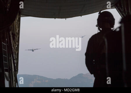 Airman 1st Class Matthew Pfeffer, 36th Airlift Squadron C-130J loadmaster, observes two Air Force C-130J Super Hercules’ over the Combined Arms Training Center Camp Fuji, Japan, March 26, 2018. Crewmembers with the 36th AS conducted airdropping a Container Delivery System (CDS) bundle and heavy equipment pallets to prepare for U.S. Air Force peacetime and contingency operations. Stock Photo