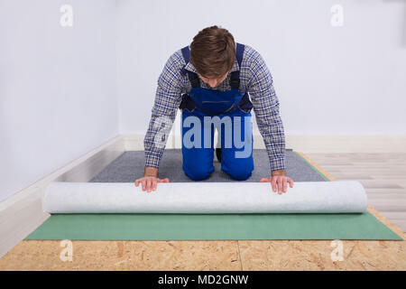 Side View Of A Young Male Worker In Overalls Installing Carpet Stock Photo