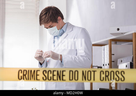 Crime Scene Do Not Cross Tape In Front Of Forensic Expert Looking For Evidence Stock Photo